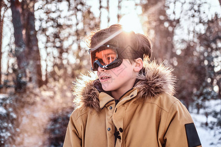 日出时身着温暖衣服和防护目镜站在雪林中的雪人滑雪图片