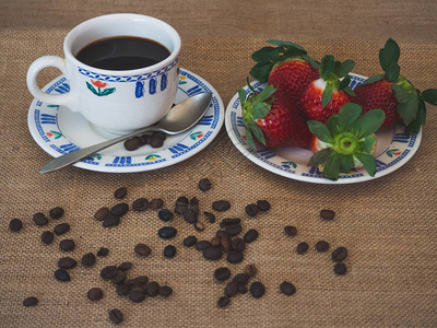 瓷茶咖啡杯旧勺子咖啡豆和盘子里的草莓图片