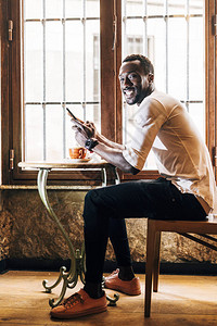 非洲男子在喝咖啡时会咨询手机校对P图片