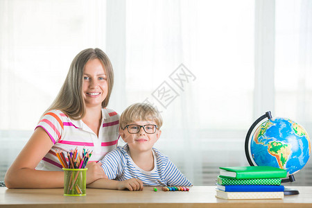 可爱的孩子在家和妈一起一家人一起做作业年轻妈帮助她的儿子图片
