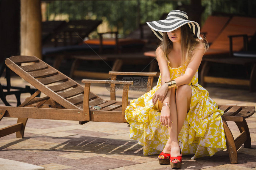 女人在户外躺椅上放松戴帽子的女士夏天的年轻女穿着黄色图片