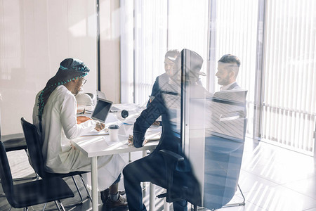 由不同年龄的商业伙伴组成的多种族团队在现代宽敞且光线充足的办公室的会议室中互动图片