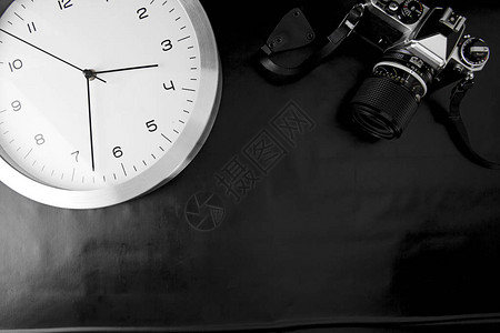现代设计墙钟与黑色背景的古代相机邻图片