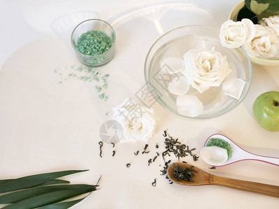 水中的白玫瑰花瓣绿色水果海盐轻桌上的绿茶顶视图面膜成分温图片