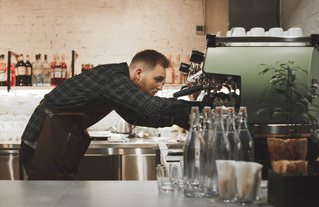 一位大胡子咖啡师的肖像在烹饪后清洁专业咖啡机调酒师正在咖啡图片