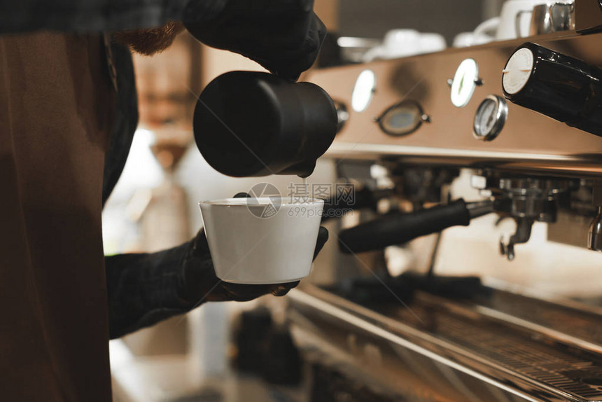咖啡师将牛奶倒入咖啡热饮近距离观看咖啡店老板在杯子里倒牛奶煮咖图片