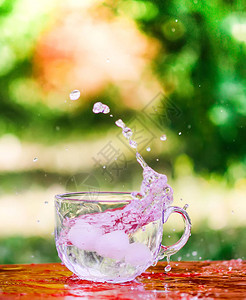 夏日在桌外的透明玻璃杯里喷洒着冰块和图片