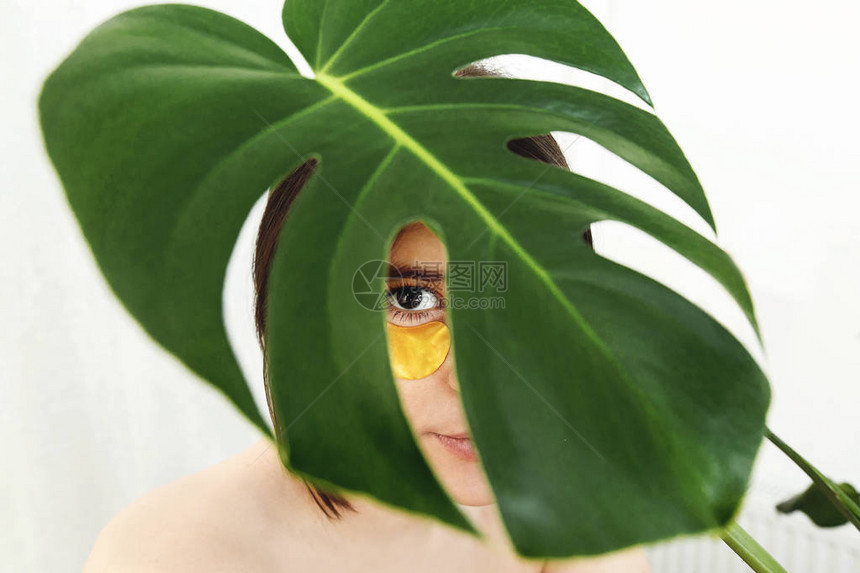 在眼睛和绿色棕榈叶下提起抗皱胶原蛋白贴片图片