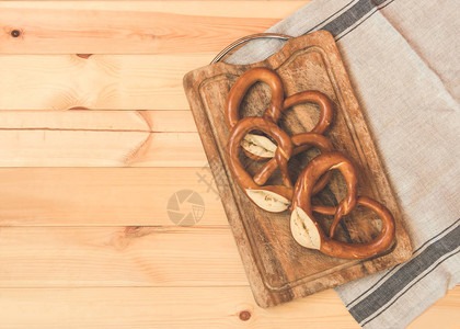 新鲜出炉的软椒盐脆饼在质朴的木制背景上的木制砧板上色调图像顶视图片