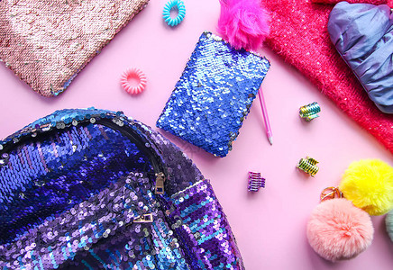 时尚配饰和连衣裙的明亮组合闪光亮片糖果钱包背包彩色绒球和发带柔和的粉红色柔和背景上的不同对象背景图片