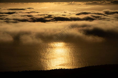 黑暗海岸线附近海洋中黄金日落反图片