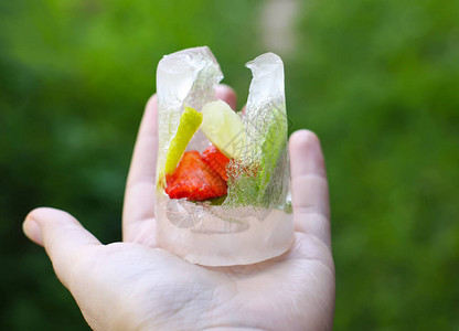 用草莓柠檬和新鲜的绿薄荷叶融化冰块在手中图片
