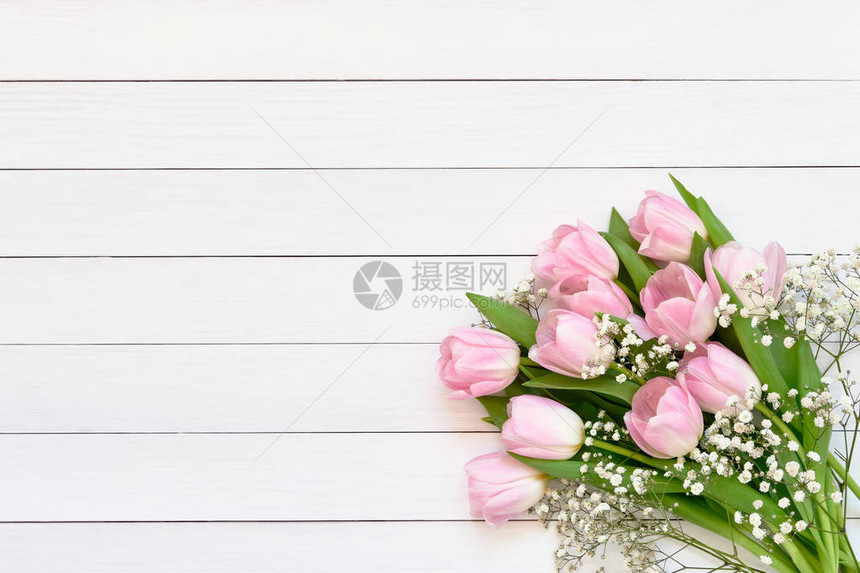 粉红色郁金香花和白木本底的吉普西拉花束图片