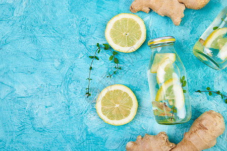 时尚排毒健康饮品在蓝色背景的成分生姜柠檬薄荷的瓶子里排毒夏季饮料图片