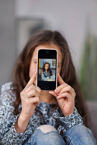 年轻的少女用她的智能手机拍了一张自拍照片图片