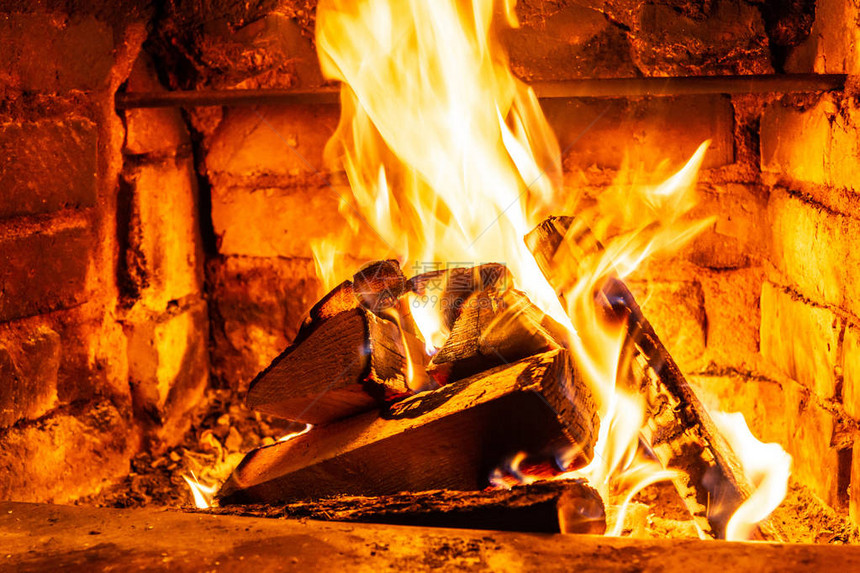 在火中燃烧的木柴在壁炉中燃烧砖炉从烧焦的原木中提供热量和热量燃烧的煤和火焰图片