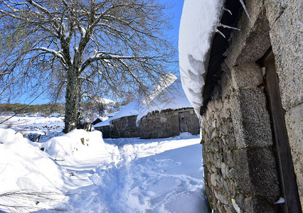 西班牙用石头和稻草建造的古老的白雪皑的帕洛萨房屋有冰柱的屋顶图片