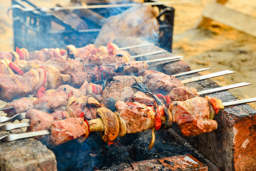 油炸多汁的肉在火上烤串从砖的火盆木炭和火焰烤架野图片