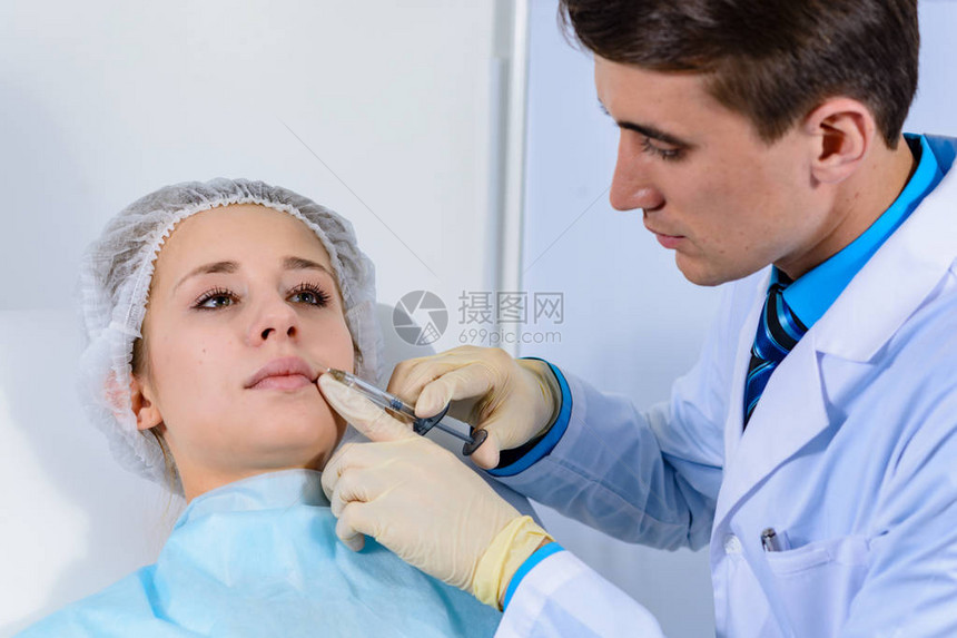 美容师的手在脸上嘴唇上注射年轻女子在沙龙接受美容面部注射面部老化年轻化和保湿程序美图片