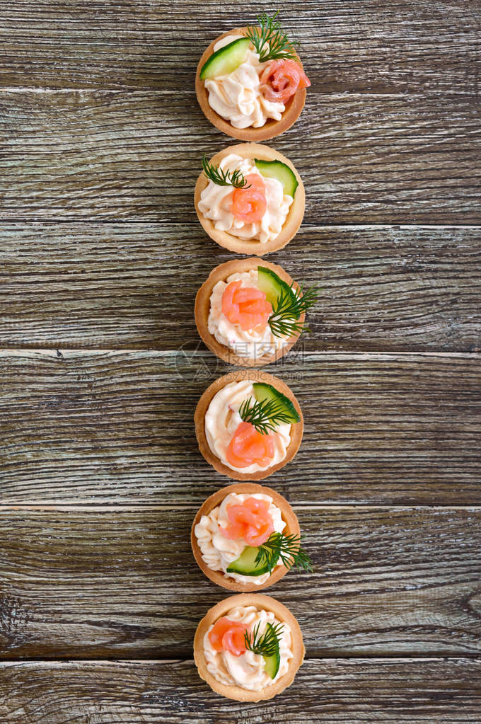 有奶油酪和咸鲑鱼的塔特饼在木制背景上美味的派对小点心手指食图片