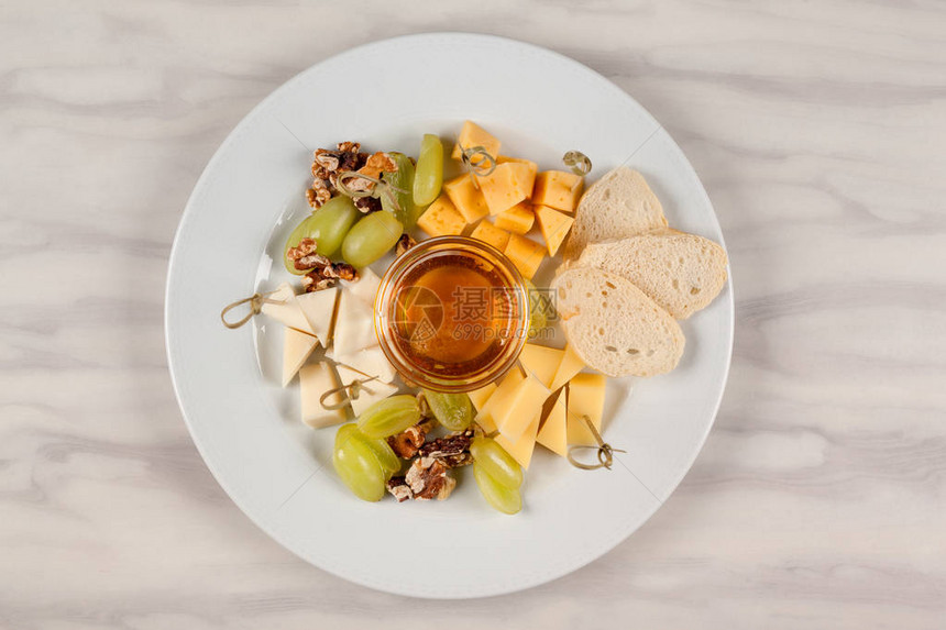 奶酪拼盘白盘上放着蜂蜜和葡萄图片