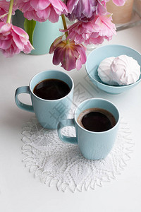两杯黑咖啡和一份美味的早餐棉花糖紧挨着一束美丽的花瓶中的粉红图片