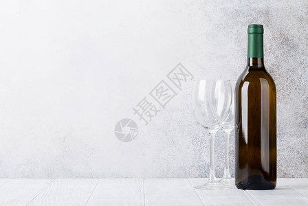 石墙前的白葡萄酒瓶和玻璃杯为您的文字留出空间图片