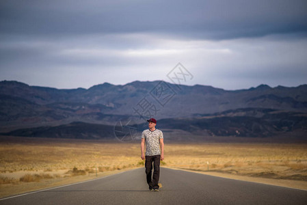 年轻人独自走在谷公园沙漠的一条空旷街道上图片