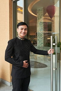 穿优雅黑色西装的亚洲男子打开酒店图片