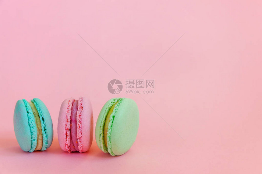 甜杏仁五颜六色的独角兽蓝绿色粉红色马卡龙或马卡龙甜点蛋糕隔离在时尚的粉红色柔和背景上法国甜饼干最小的食品烘焙概图片