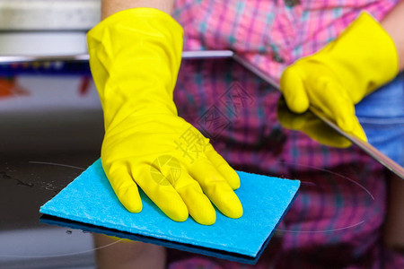 黄色橡胶保护手套中的女清洁电锅炉表面的图片