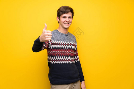 黄墙上的青少年男子用拇指举起因图片