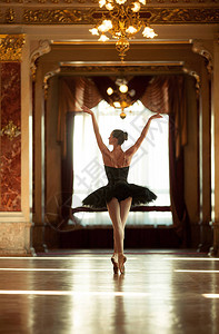 美丽的芭蕾舞女在豪华的大厅里跳舞穿着黑色礼服的吊灯机图片