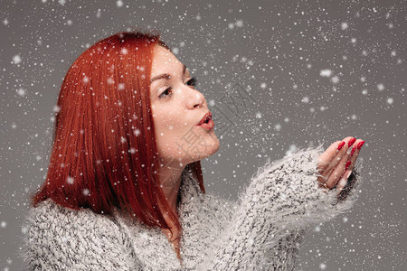 穿着灰色毛衣的漂亮女人在下雪时会追逐明星和许愿图片