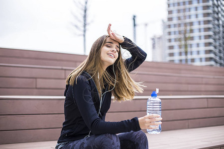 女青年在健身后和户外喝水时背景图片