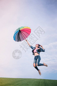 跳女孩拿着雨伞彩色天空背景自然公园图片