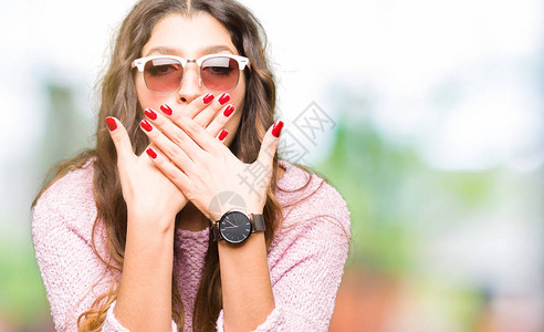 穿着太阳镜和粉红色毛衣的年轻美女被手用大错特的手图片