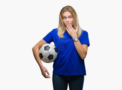 年轻的白种女人拿着足球在与世隔绝的背景上捂着嘴图片