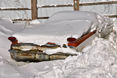 一辆老旧的生锈车被埋在雪地里图片