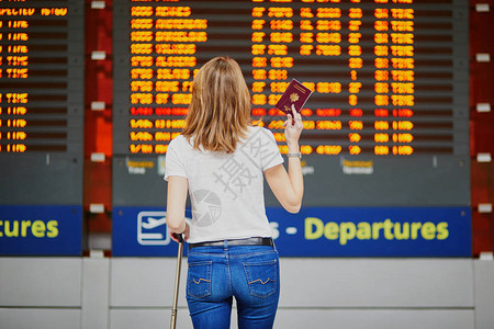 国际机场年轻女子在航班信息显示附近携图片