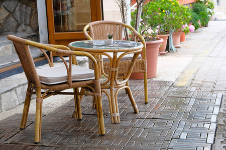 拉坦桌椅在咖啡馆的户外夏季花盆中图片