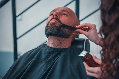 用电动剃须刀理发的男头发修剪器发型的特写理发师用理发剪头发用电动剃须图片