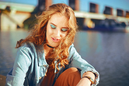 美丽的女孩坐在河边的码头上图片