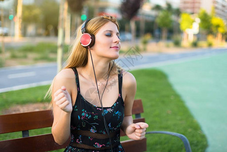 公园里的年轻美少女听着音乐用耳机图片