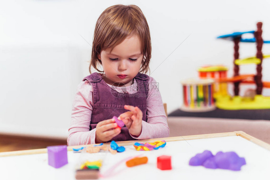 小女孩在玩塑料却坐在幼稚室的桌子上图片