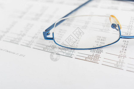 桌子上的财务图表上的眼镜图片