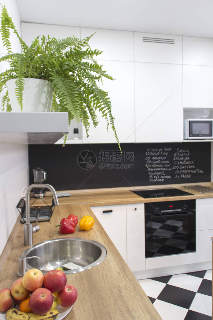 斯堪的纳维亚风格的现代白色u形厨房厨房里的架子上放着植物和罐子春季装饰蕨类棋盘图片