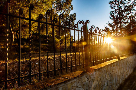 傍晚的阳光照在公园里的旧铁栅栏上图片