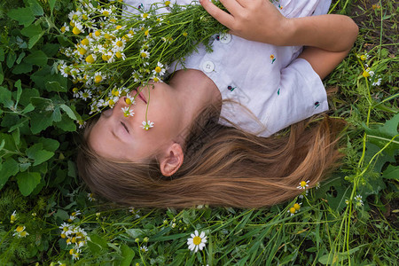 穿着白裙子的金发美女躺在绿色草地上图片