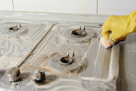 手戴黄色手套清洗煤气炉用厨房用具概念和清洁燃气灶春季大扫图片